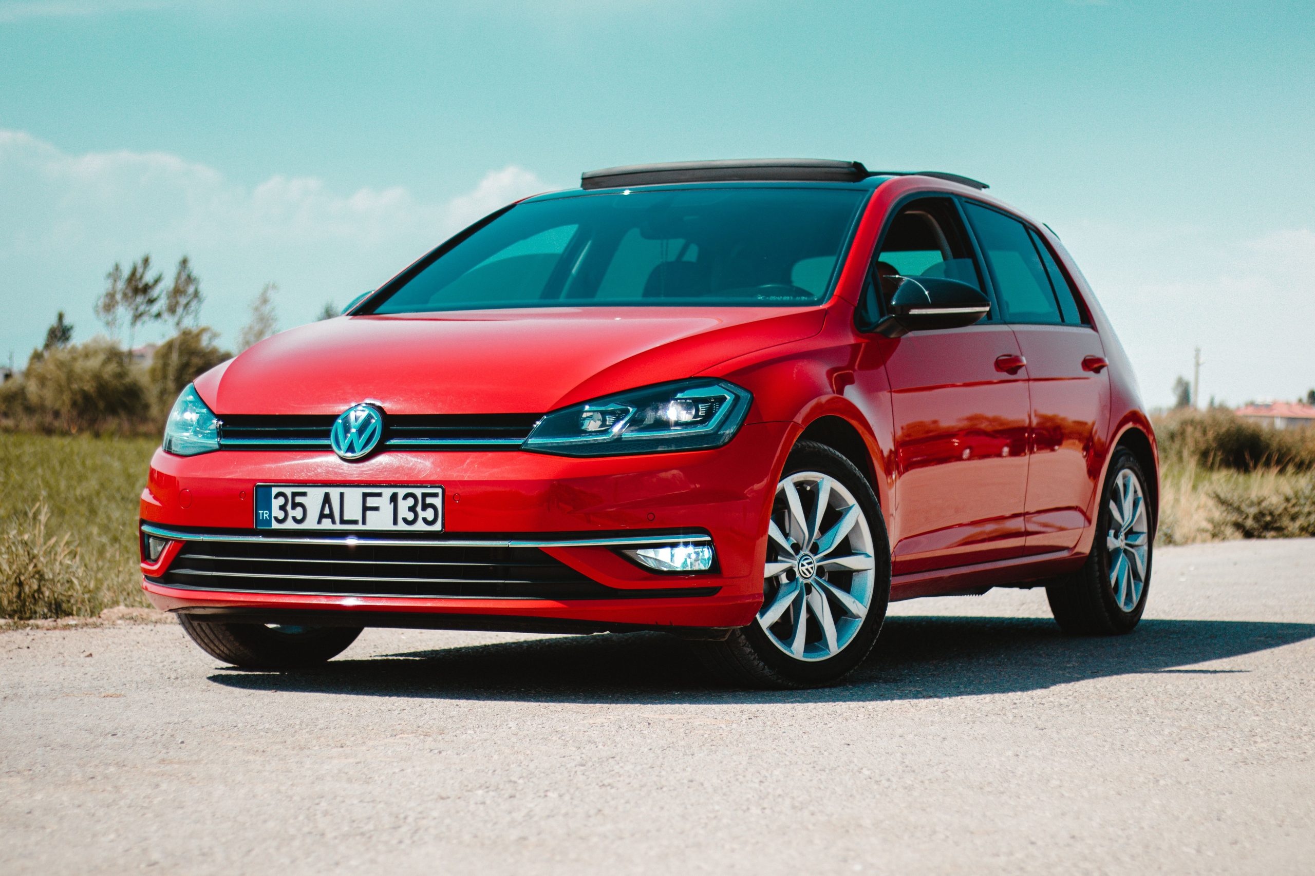 Volkswagen rouge garée sur route rurale ensoleillée