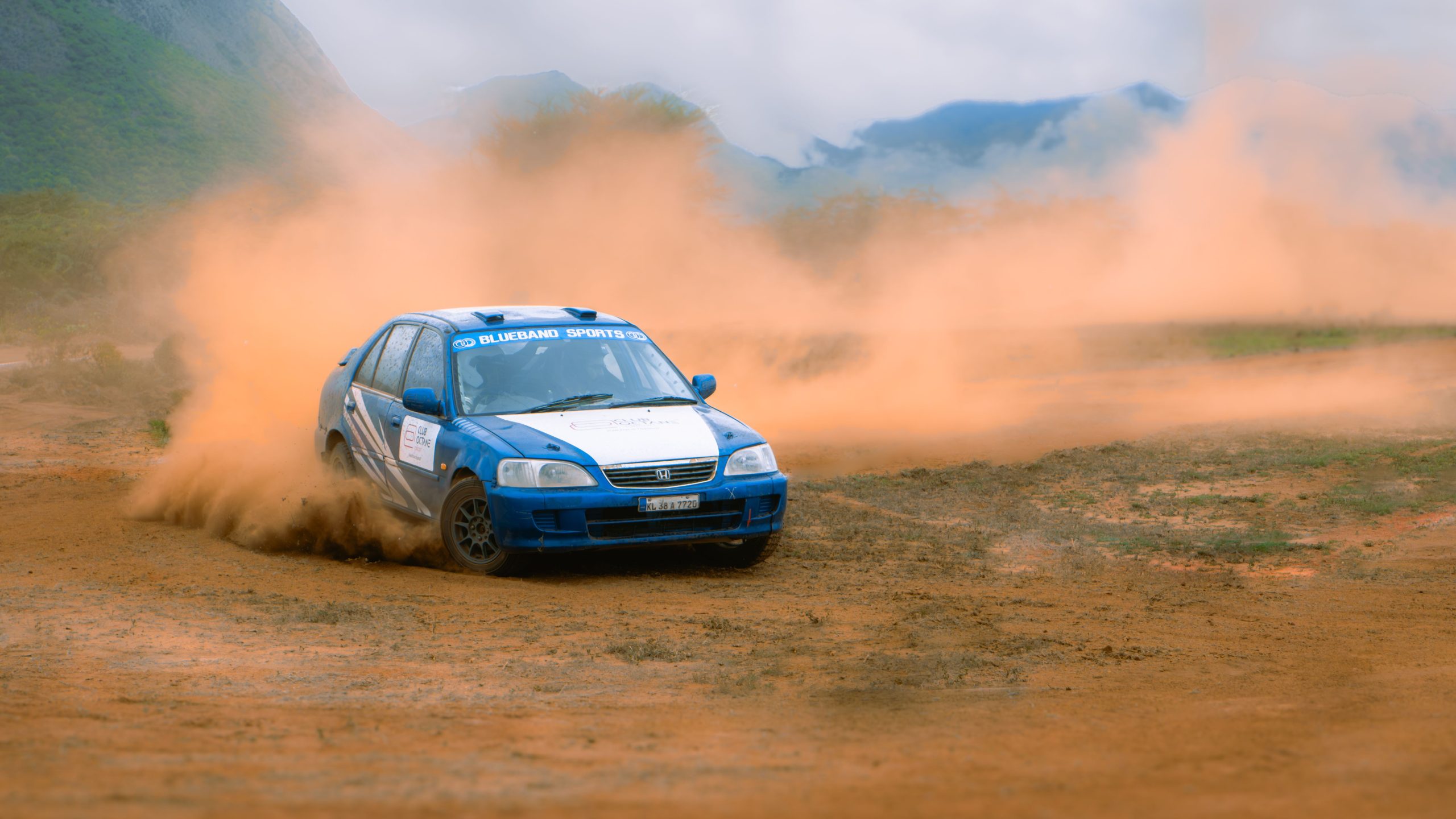 Bolide bleu accélère sur piste terre poussiéreuse