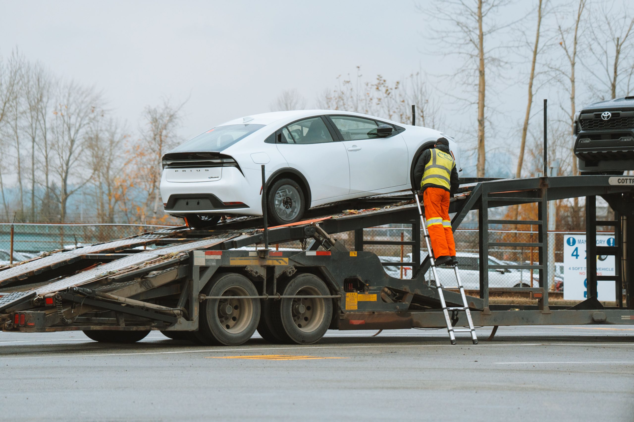 Ouvrier chargeant une voiture blanche sur camion