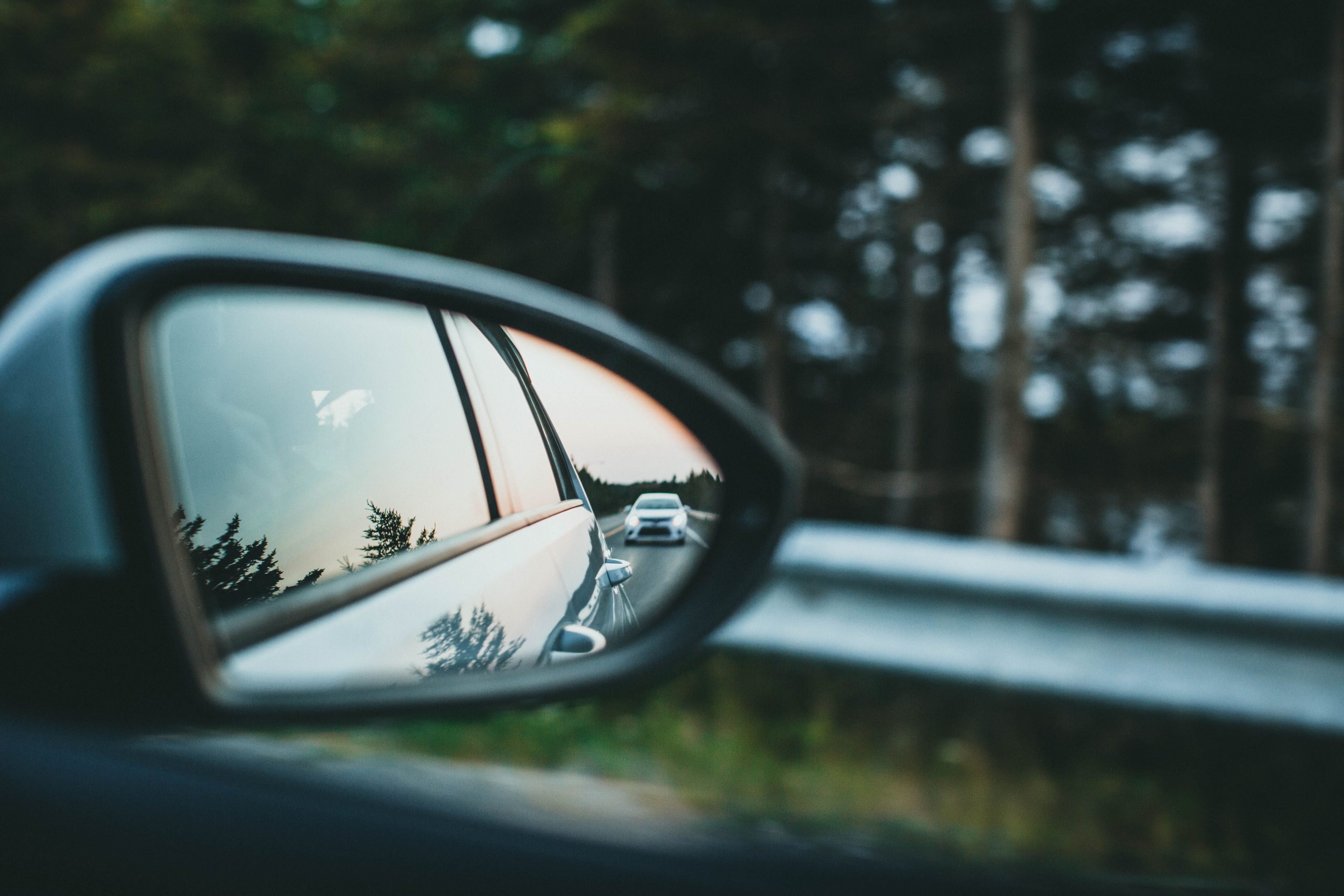 Voiture reflétée dans rétroviseur route forestière