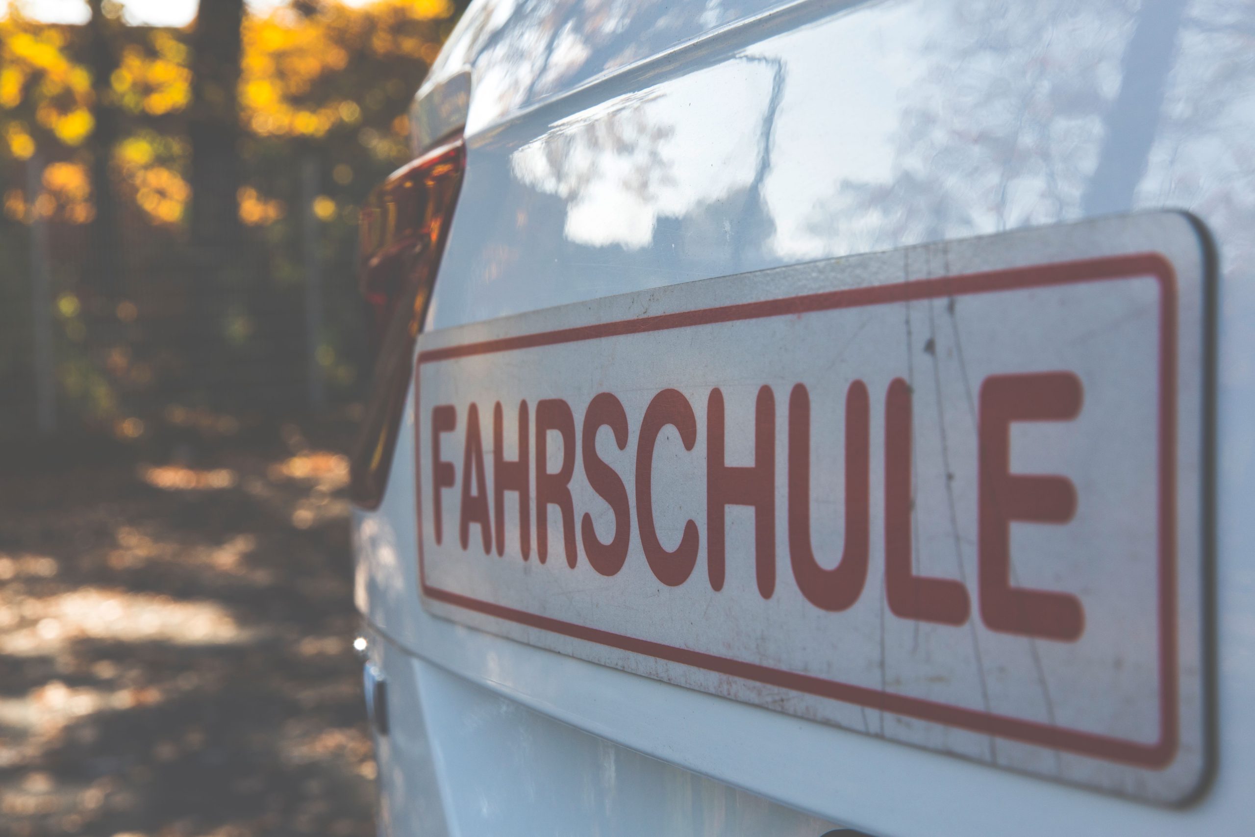 Voiture blanche avec panneau auto-école en automne