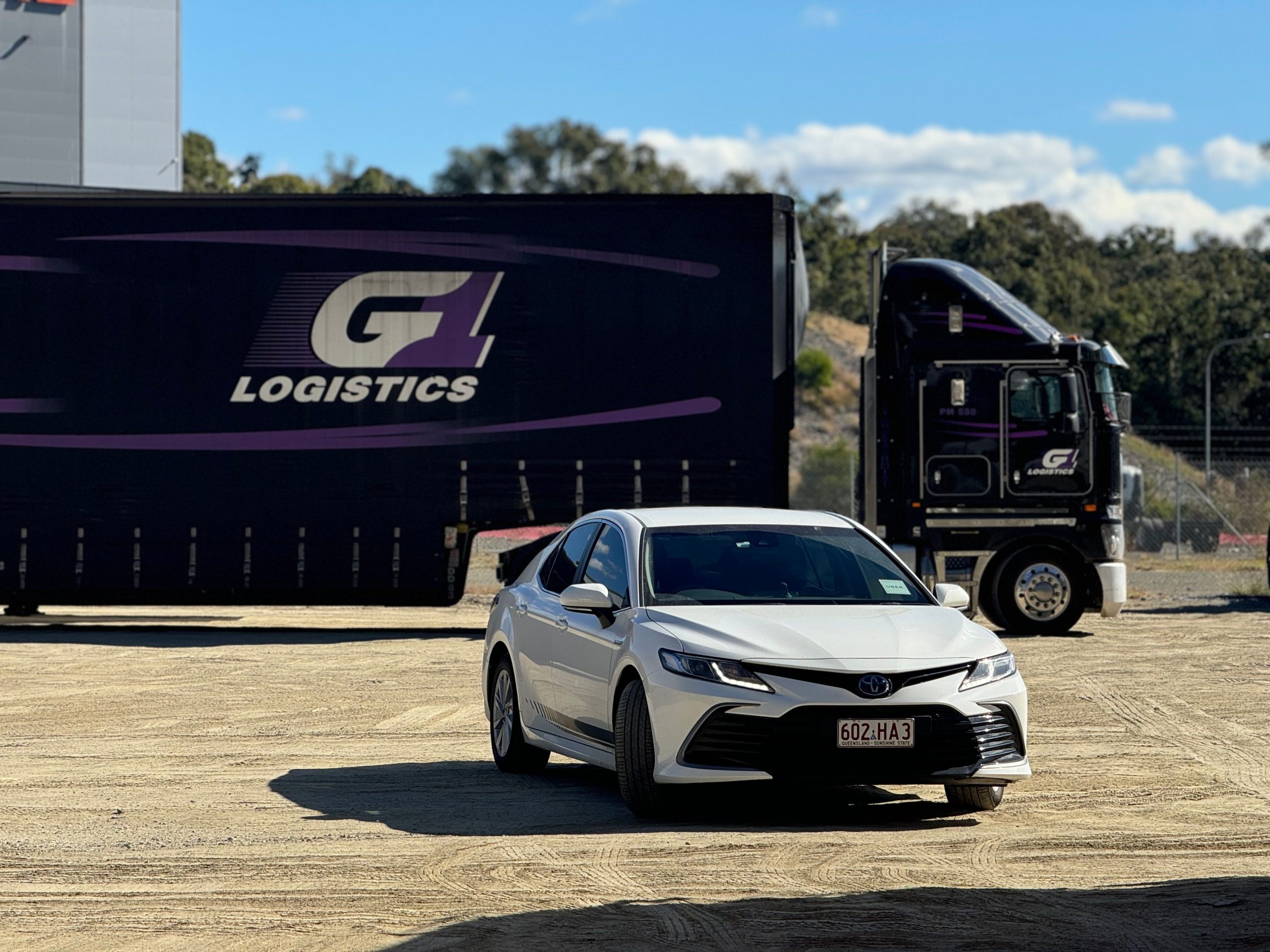 Berline blanche devant camion logistique chargement