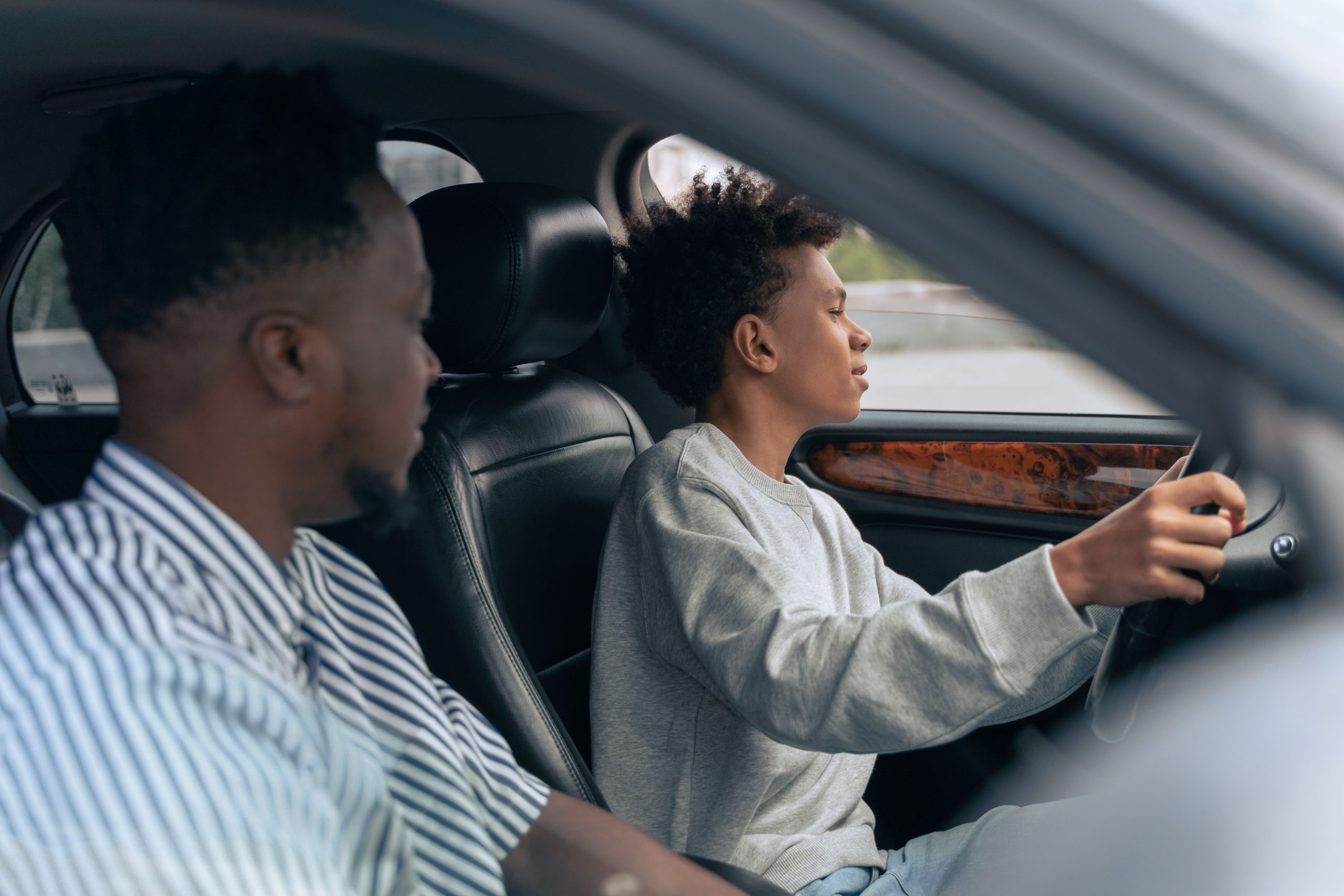 Père enseignant la conduite à son fils en voiture.